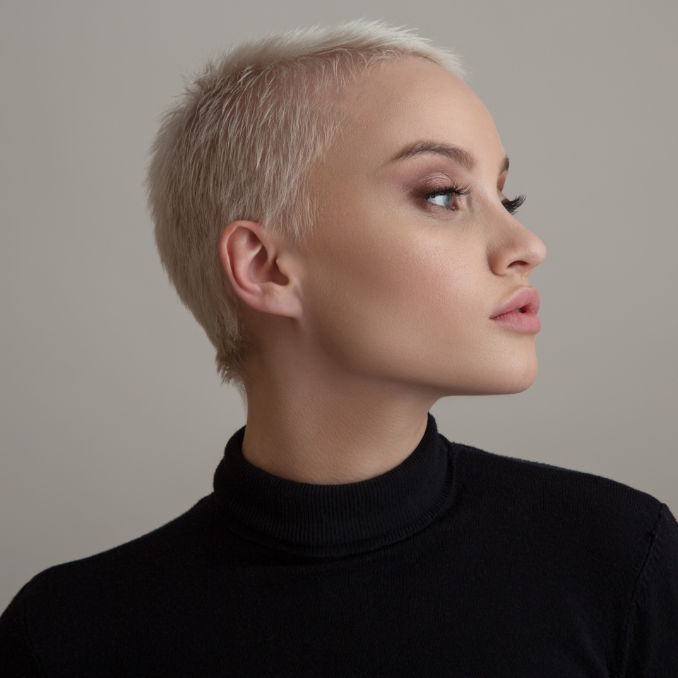 Portrait of a beautiful blonde woman with a short hair on a gray background.