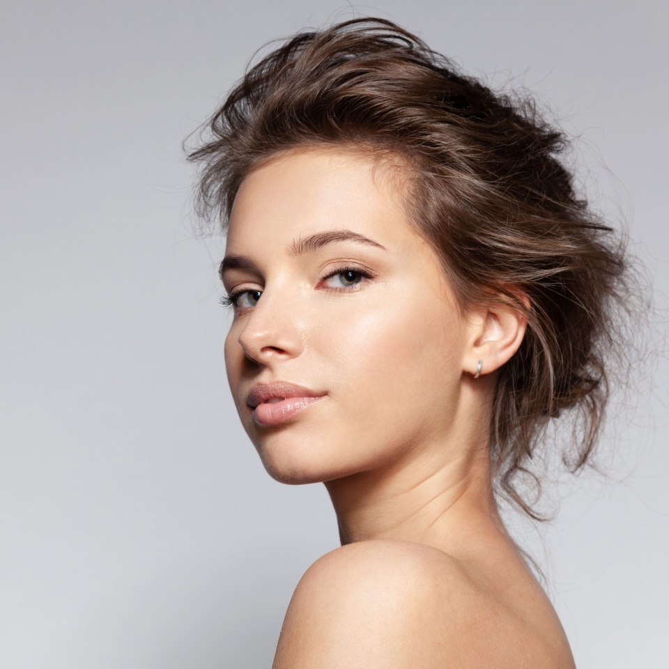 Portrait of beautiful young caucasian female with bare shoulder on gray background with copyspace for ad. Pretty millennial girl model with clean healthy moisturized skin. Natural beauty concept
