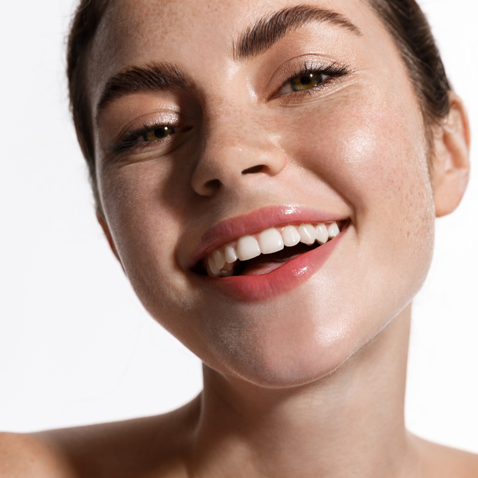 Beauty face of woman touch clean and fresh hydrated skin, perfect facial nude makeup and smile, standing naked shoulders. Girl advertising cosmetics with spf sun protecting, botanical ingredients