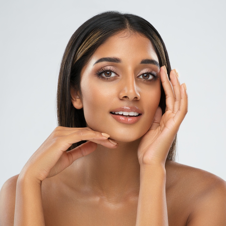 Beautiful Girl Facial Skin Care. Smiling Indian Model with Perfect Eyes Make up isolated White. Women Beauty Spa Cosmetology and Treatment. Face Lift and Dermal Filler Cosmetics