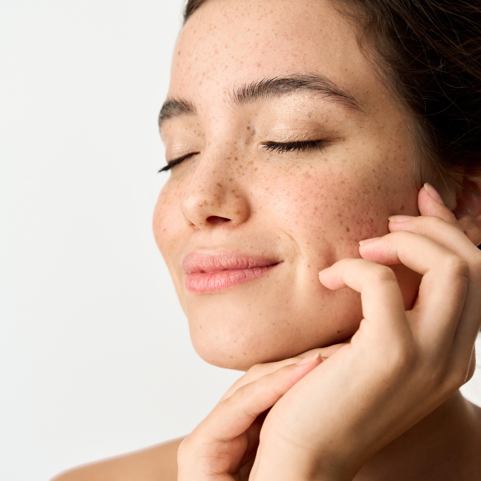 Aesthetic beauty photo of smiling young woman with freckles on face enjoying fresh clean healthy skin advertising skincare sunscreen cosmetics. Happy brunette Latin girl isolated on white background.