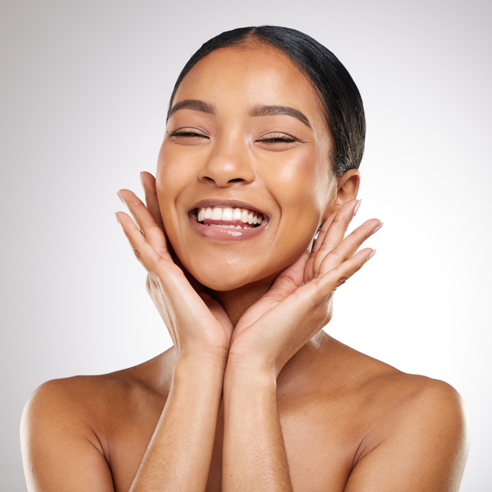 Skincare, beauty and woman with hands on face, smile and benefits of cosmetics in studio. Healthy, dermatology and girl with natural makeup for glow on skin and self care portrait on white background