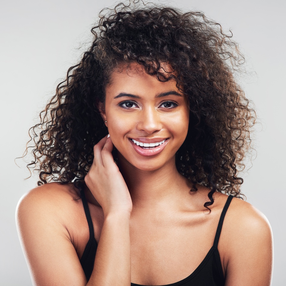 Portrait, woman and beauty in studio for skincare, natural and cosmetic on white background. Curly hair, cosmetology and facial treatment with collagen for model person, hands or texture for haircare