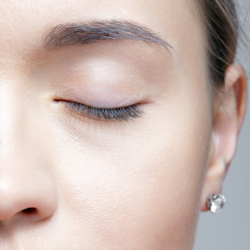 Closeup shot of half of human female face with closed eye. Woman with nude makeup of eyes or no visible makeup.